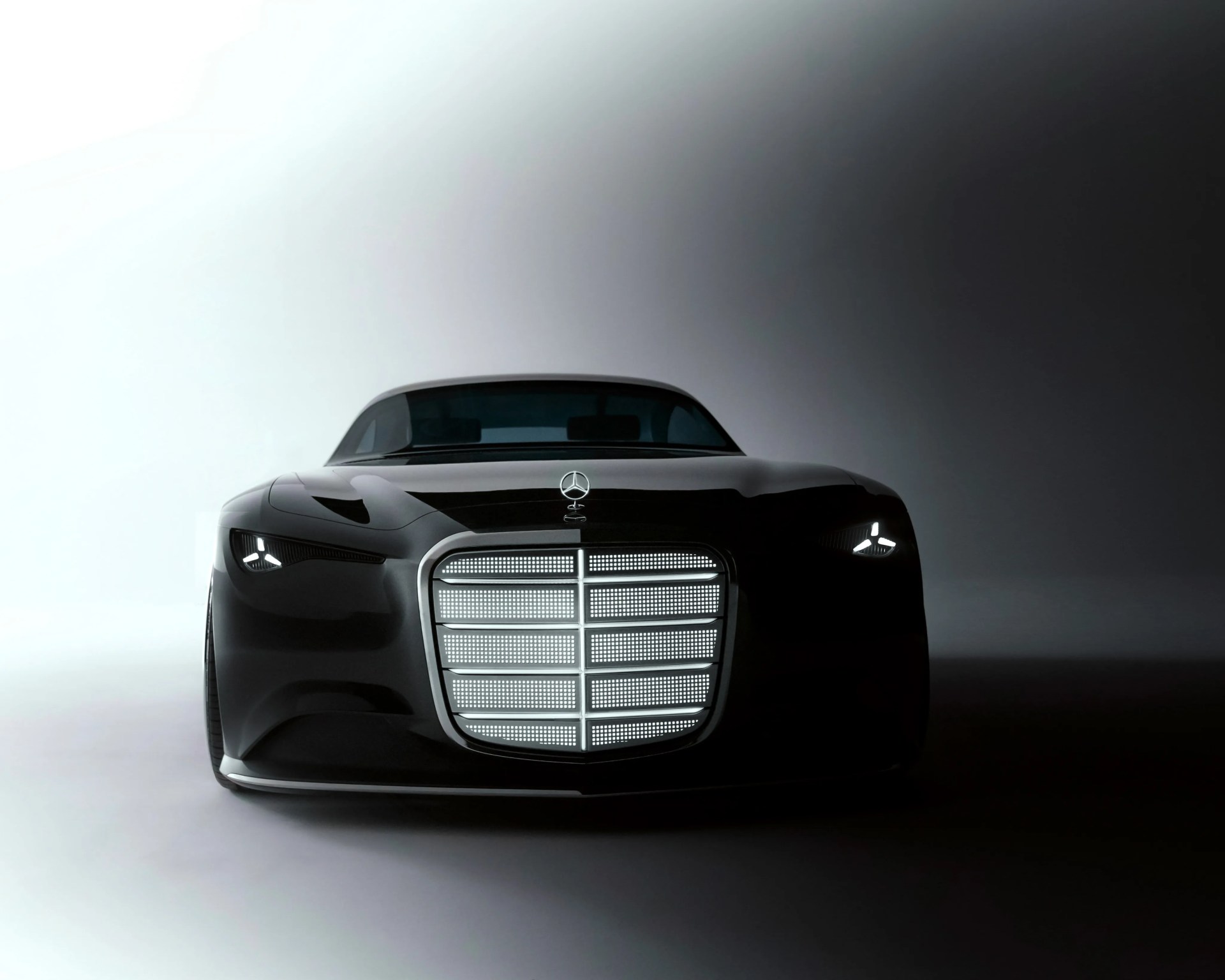 Front view of a sleek black Mercedes-Benz luxury car with illuminated grille and modern LED headlights.