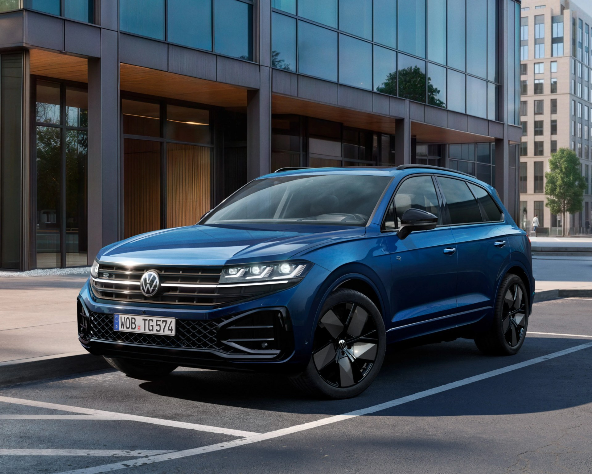 Blue Volkswagen SUV with black alloy wheels parked in an urban setting near modern glass buildings.