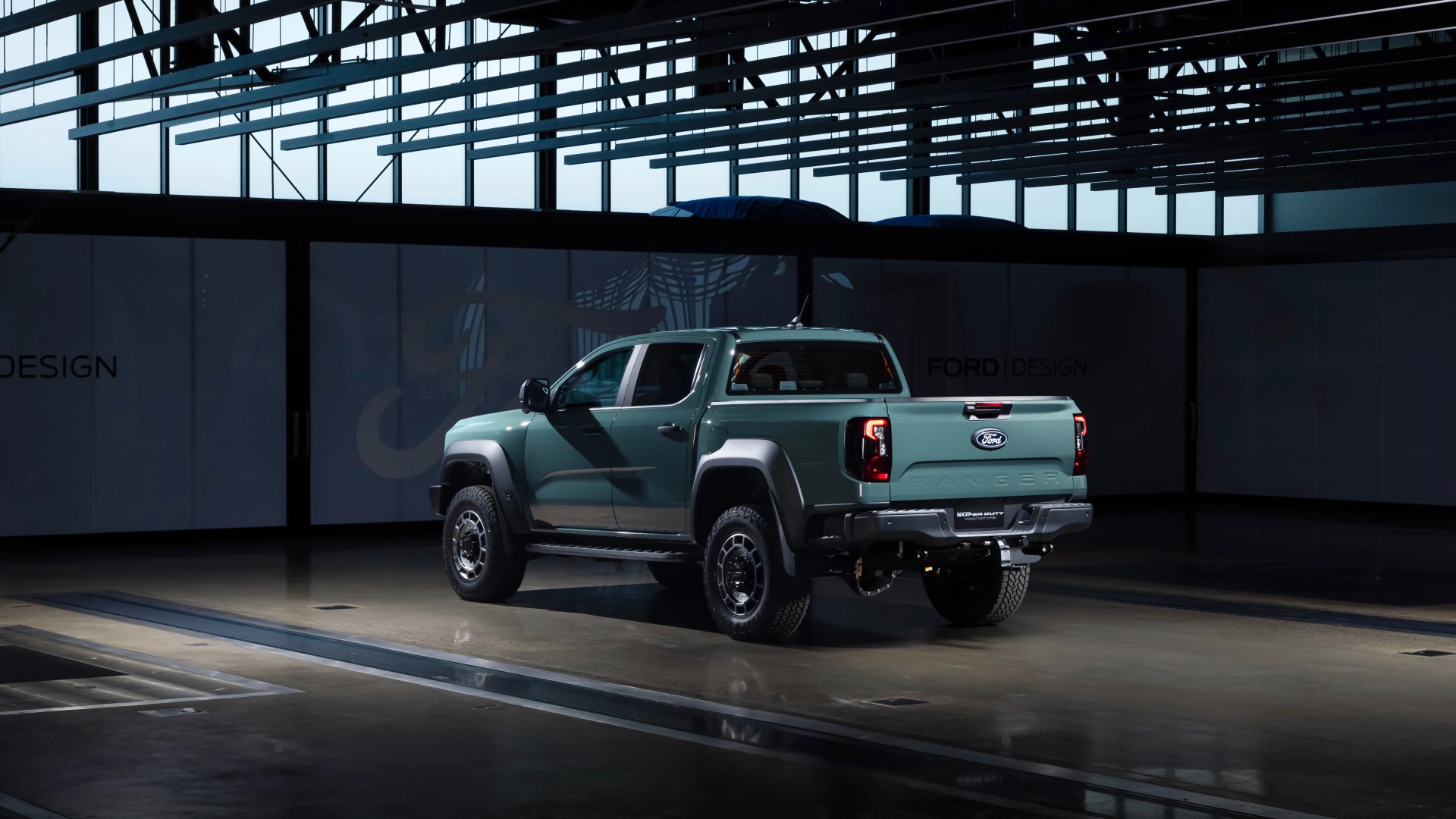 Green Ford Ranger pickup truck with black fender flares in a dark indoor showroom.