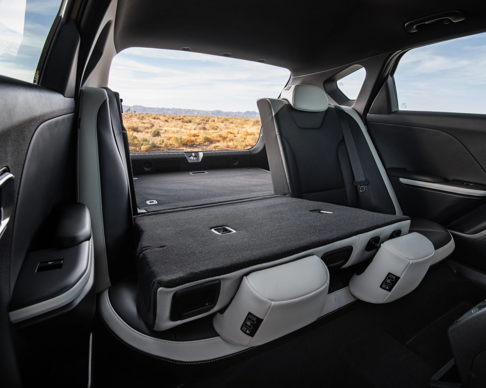 Folded rear seats in a black and gray car interior with a desert landscape visible through the rear window.