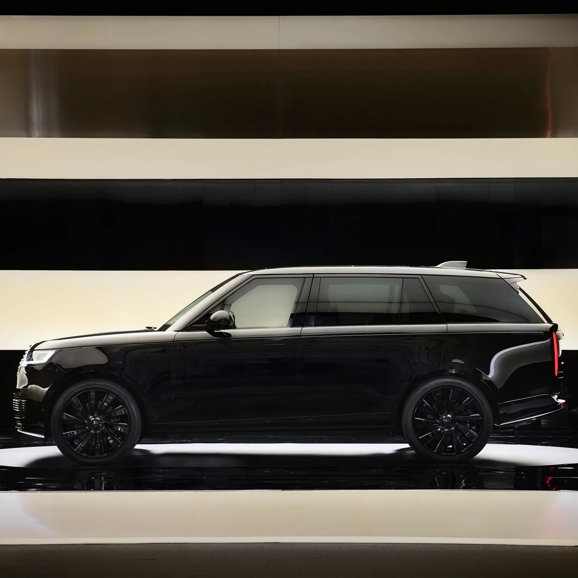 Black luxury SUV with tinted windows and black alloy wheels shown in profile against a striped black and beige background.