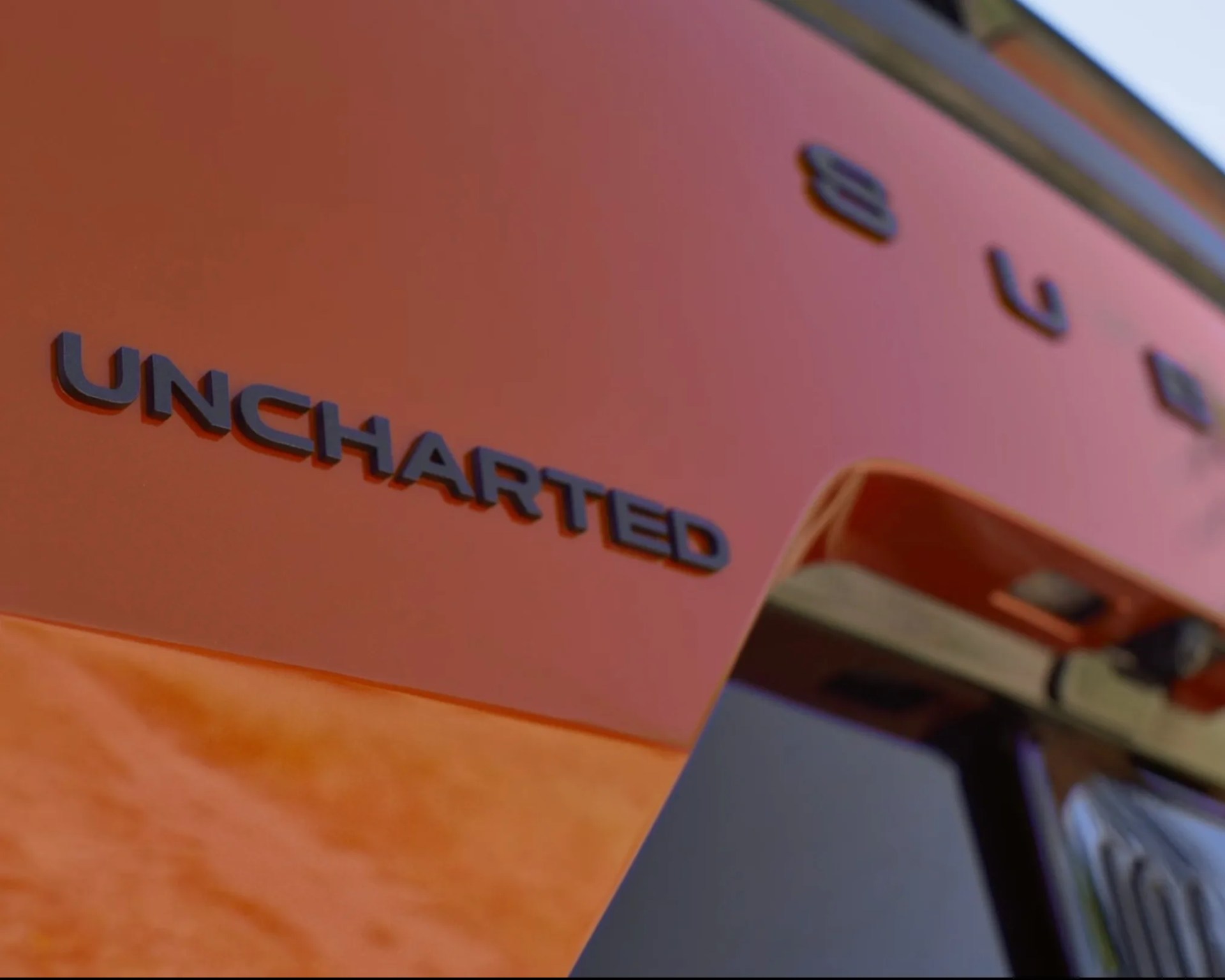 Close-up of black "UNCHARTED" lettering on an orange vehicle surface.