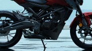 Close-up of a black and red motorcycle's engine, exhaust, and wheels on a wet surface.