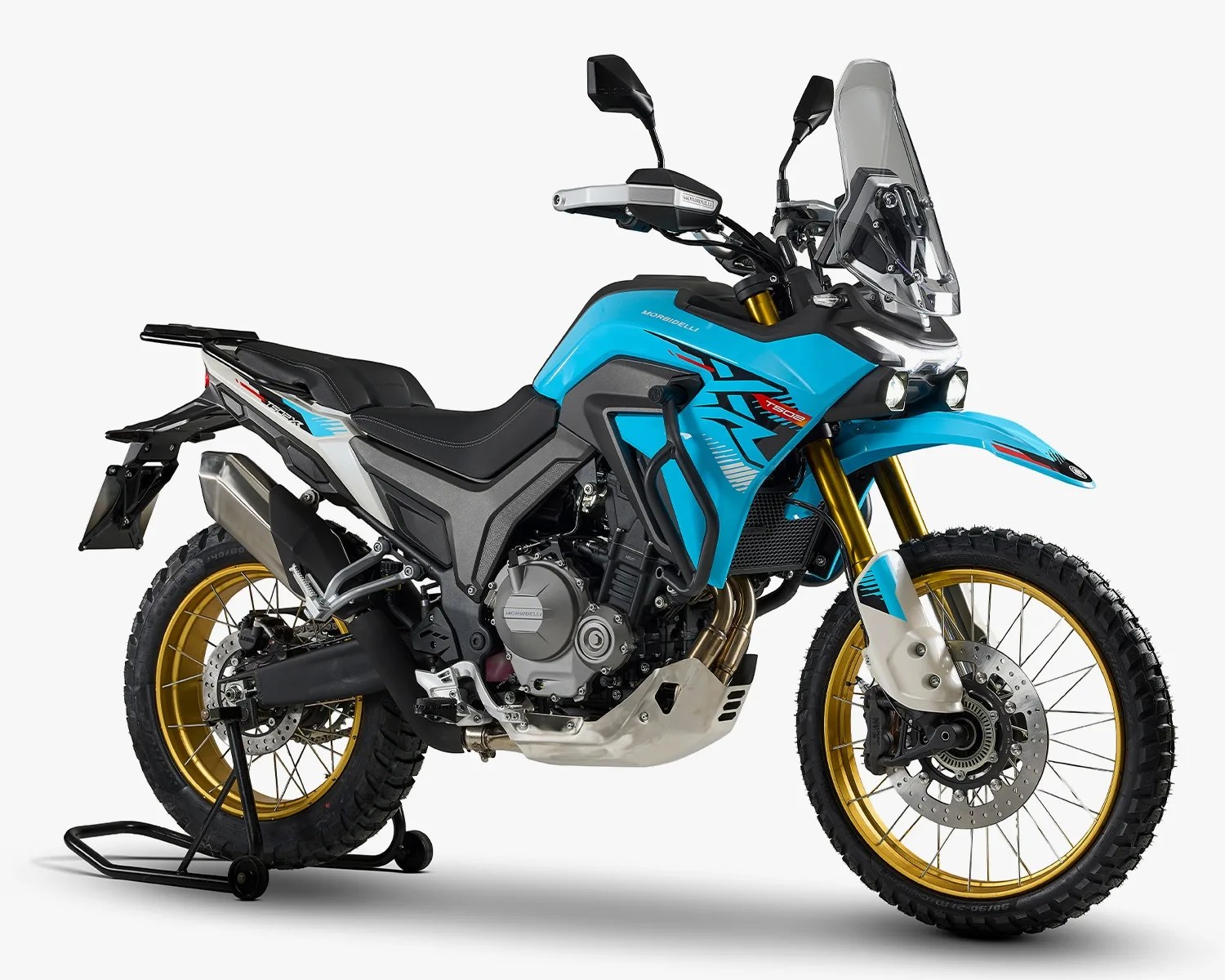 Blue and black adventure motorcycle with gold rims, knobby tires, and a tall windshield on a rear stand.