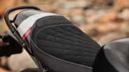 Black quilted motorcycle seat with white stitching and a gray and red accent on the rear section.