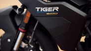 Close-up of a black motorcycle panel with "TIGER SPORT 900 TOUR" decal in white, blue, and yellow.