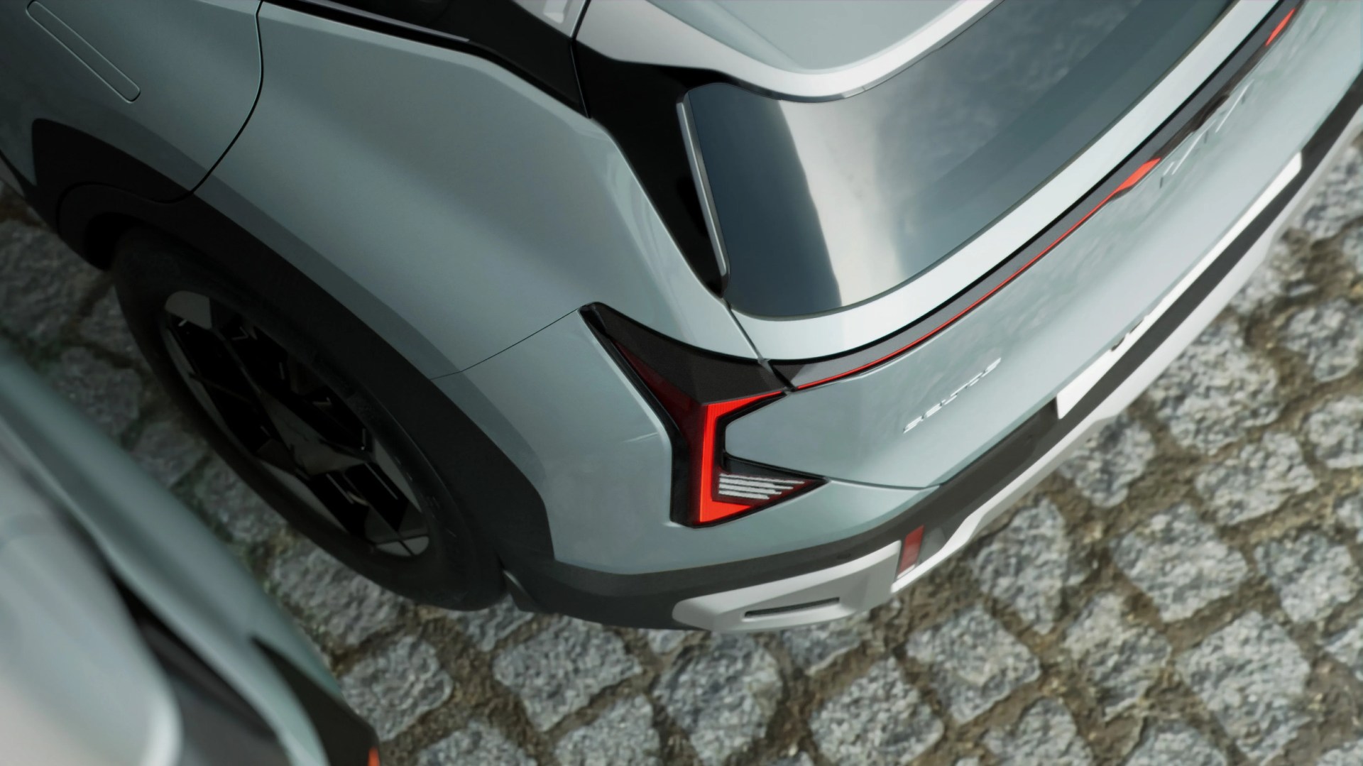 Rear corner of a silver electric SUV with angular red taillights parked on cobblestone pavement.