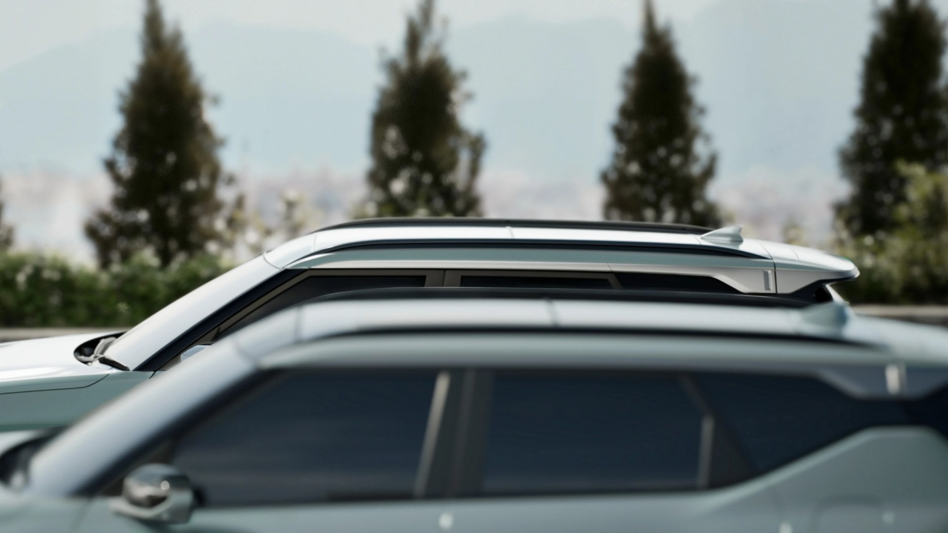 Side view of two silver SUVs parked closely with blurred trees in the background.