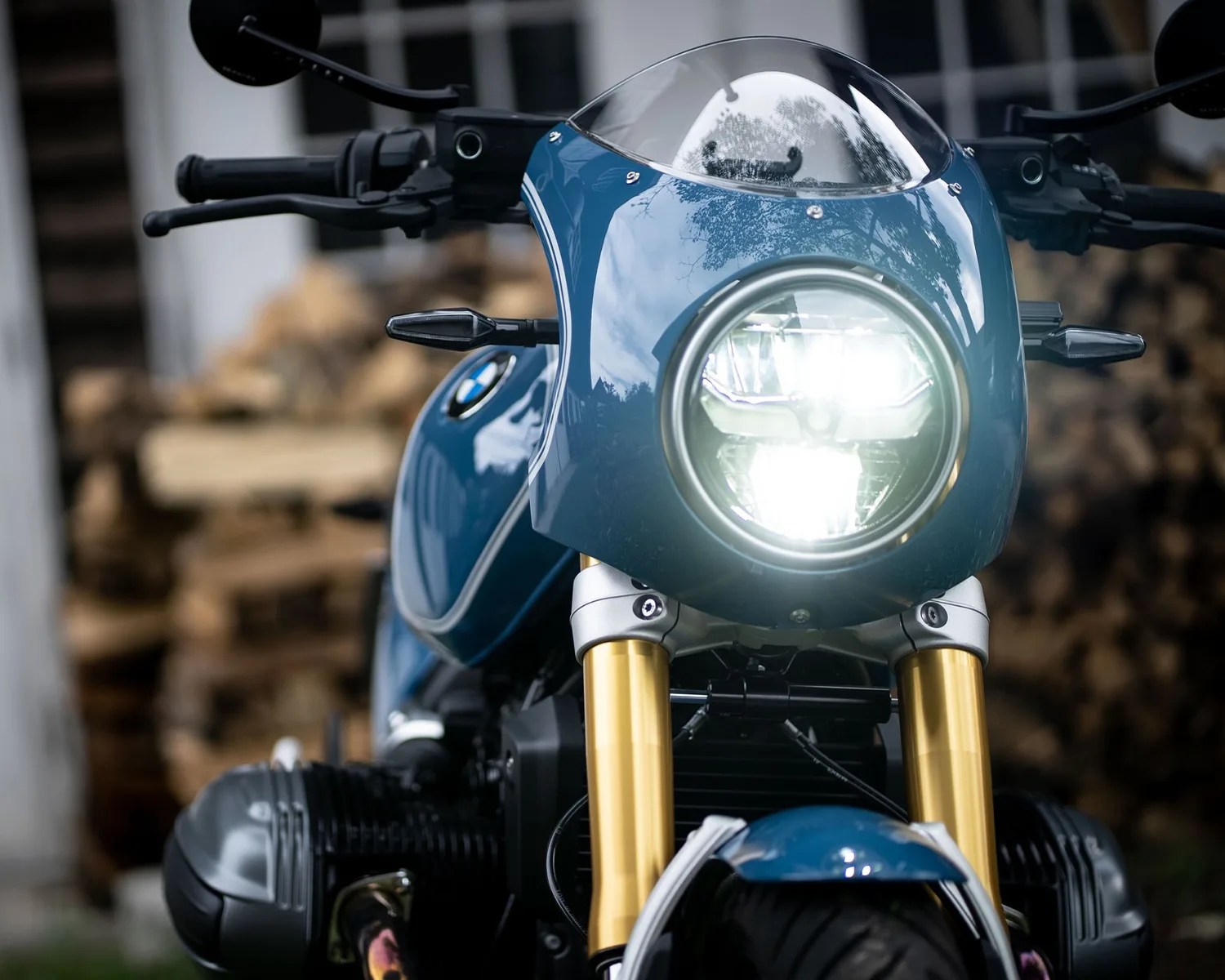 Front view of a blue BMW motorcycle with a round headlight on and gold front forks.