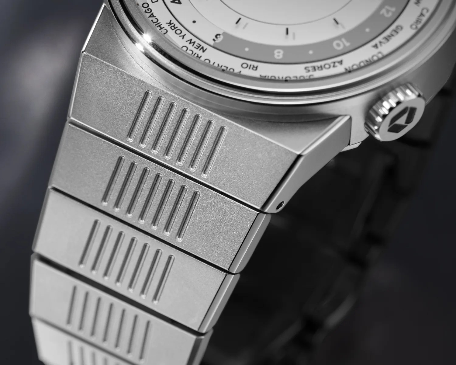 Close-up of a silver metal watch bracelet with vertical grooves and a matching silver watch case and crown.