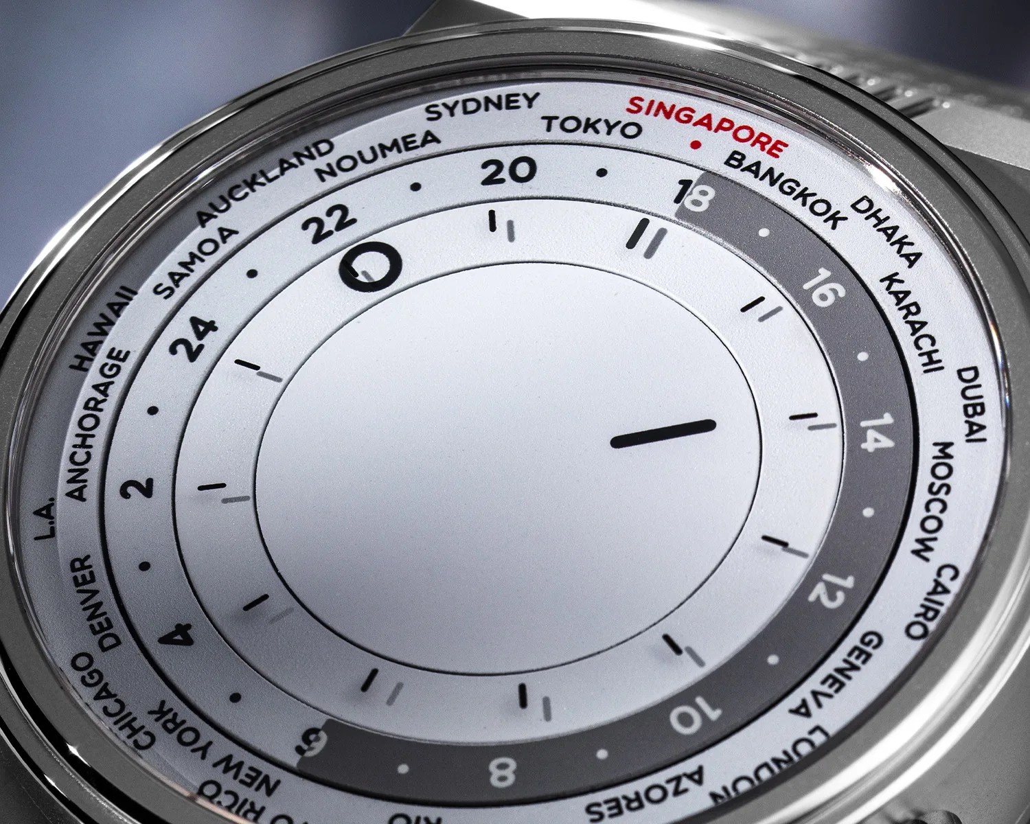 Close-up of a world time watch dial showing cities and a 24-hour scale with a silver bezel.