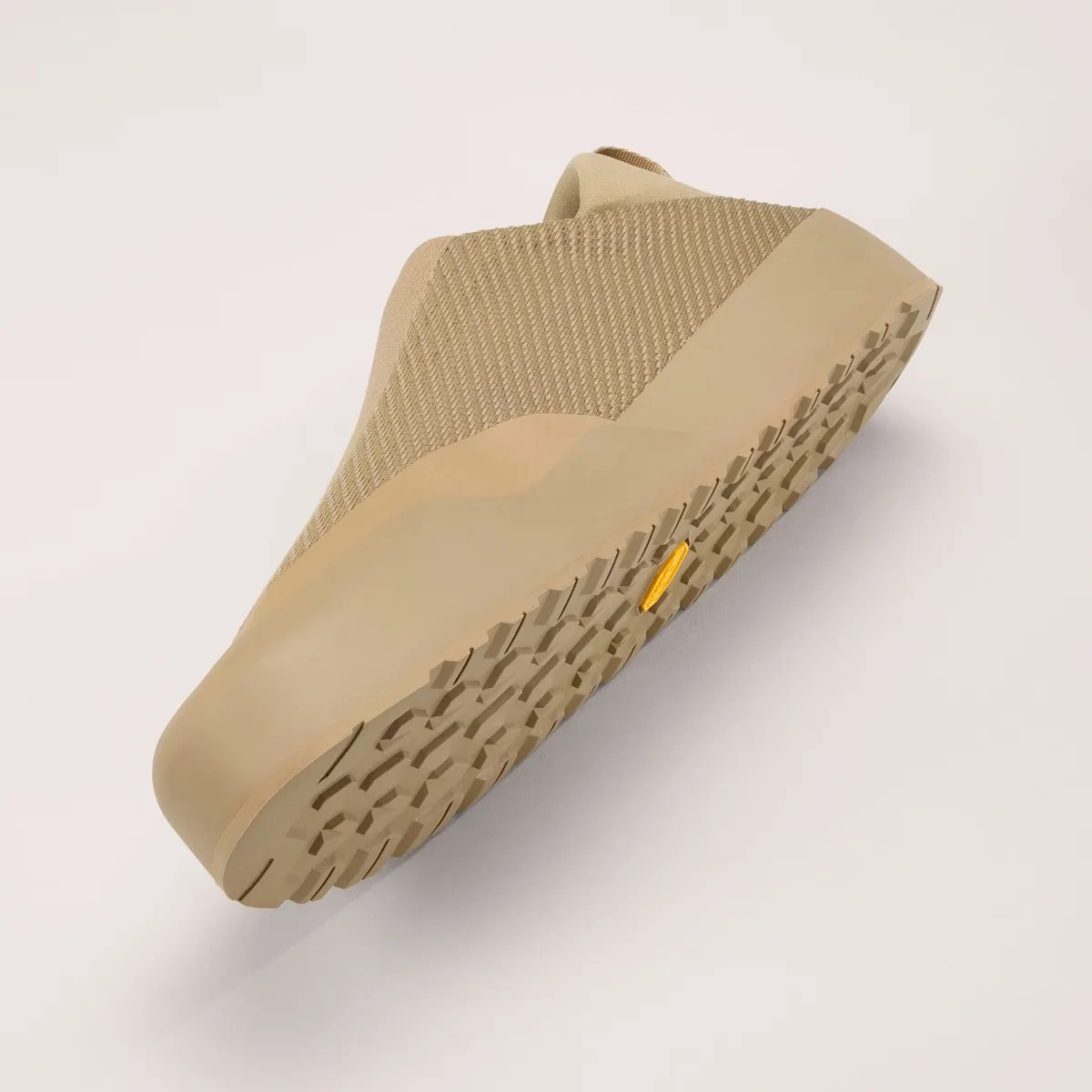 Beige slip-on shoe with textured knit upper and rugged rubber sole angled upward.