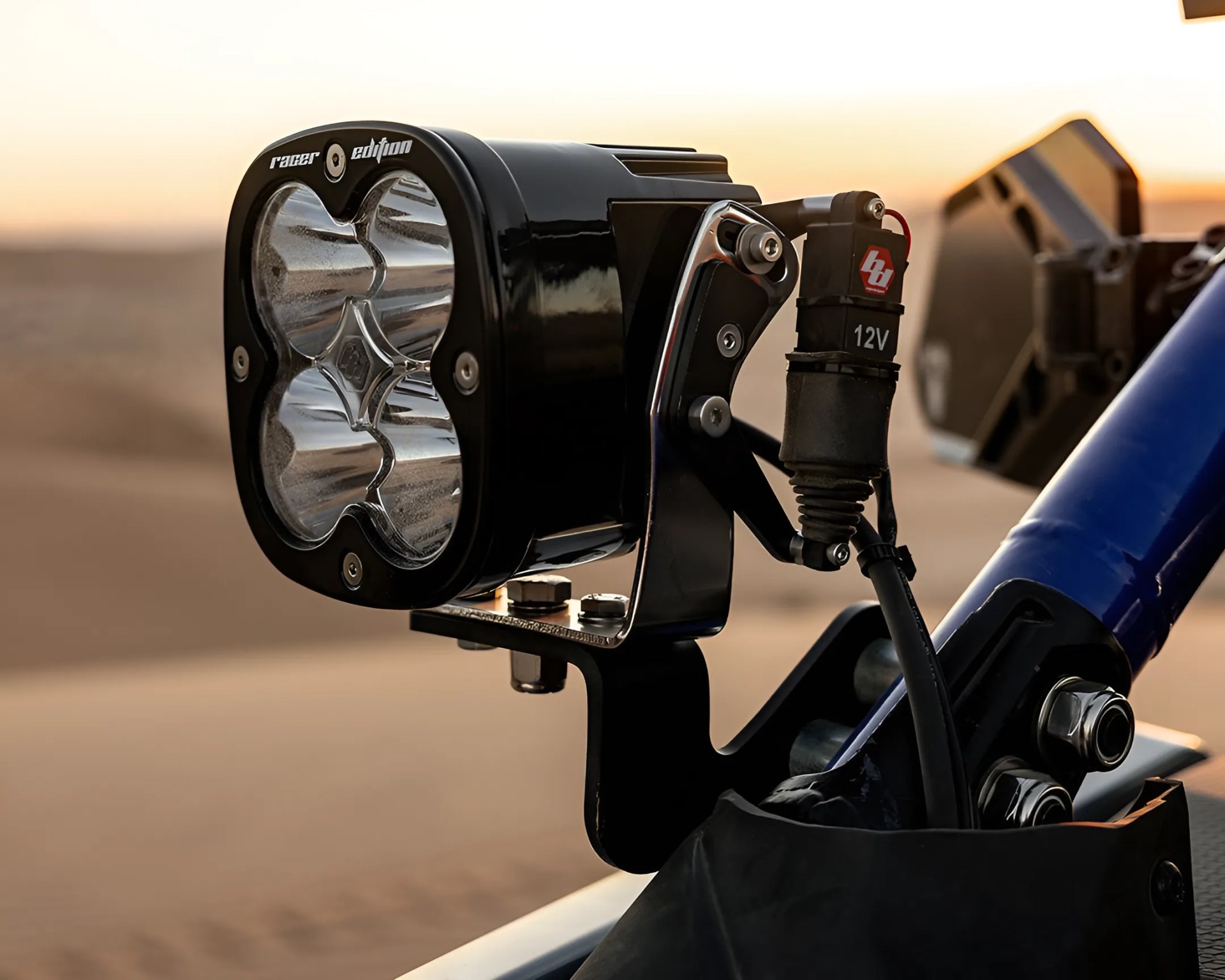 Black rectangular off-road LED light with four reflectors mounted on a blue metal frame.