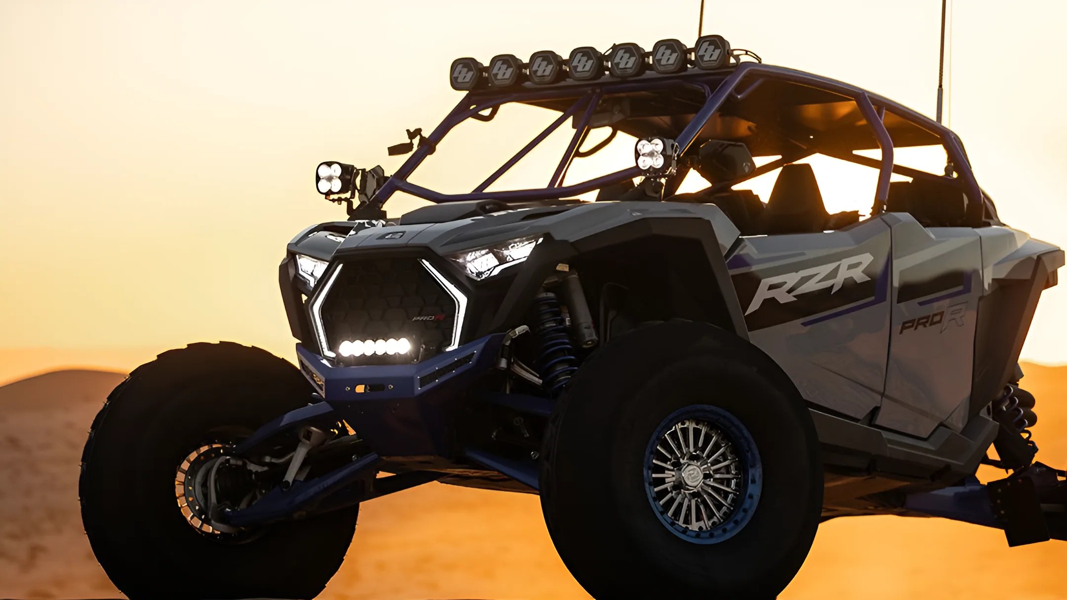 Off-road UTV with RZR Pro R branding and multiple LED lights at sunset in a desert.