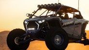 Off-road UTV with RZR Pro R branding and multiple LED lights at sunset in a desert.