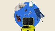 Yellow YETI cooler with black interior pockets surrounded by a blue camping chair, white tent, orange Garmin device, white lantern, black camera, corkscrew, and small brown shoe.