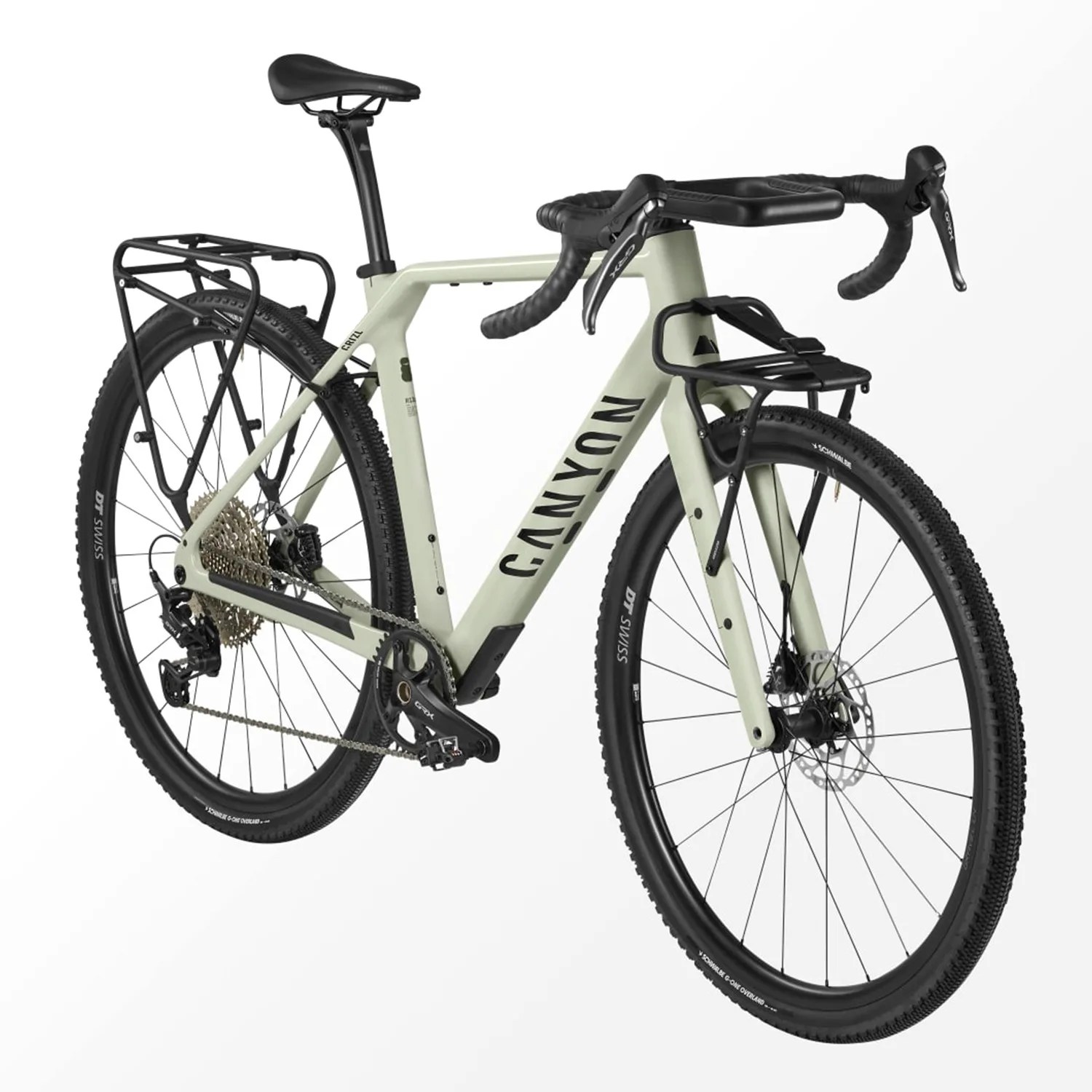 Light green Canyon gravel bike with black drop handlebars, front and rear racks, and knobby tires.