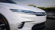 Front left side of a white electric car showing sleek LED headlights and a black grille with illuminated trim.