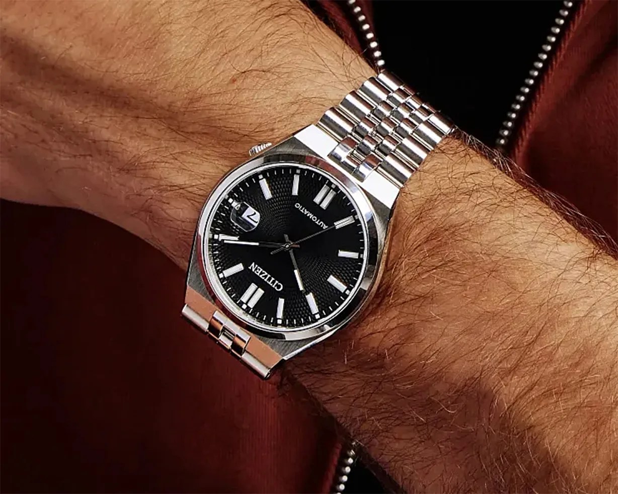 Silver metal wristwatch with black dial and white hour markers worn on a wrist.