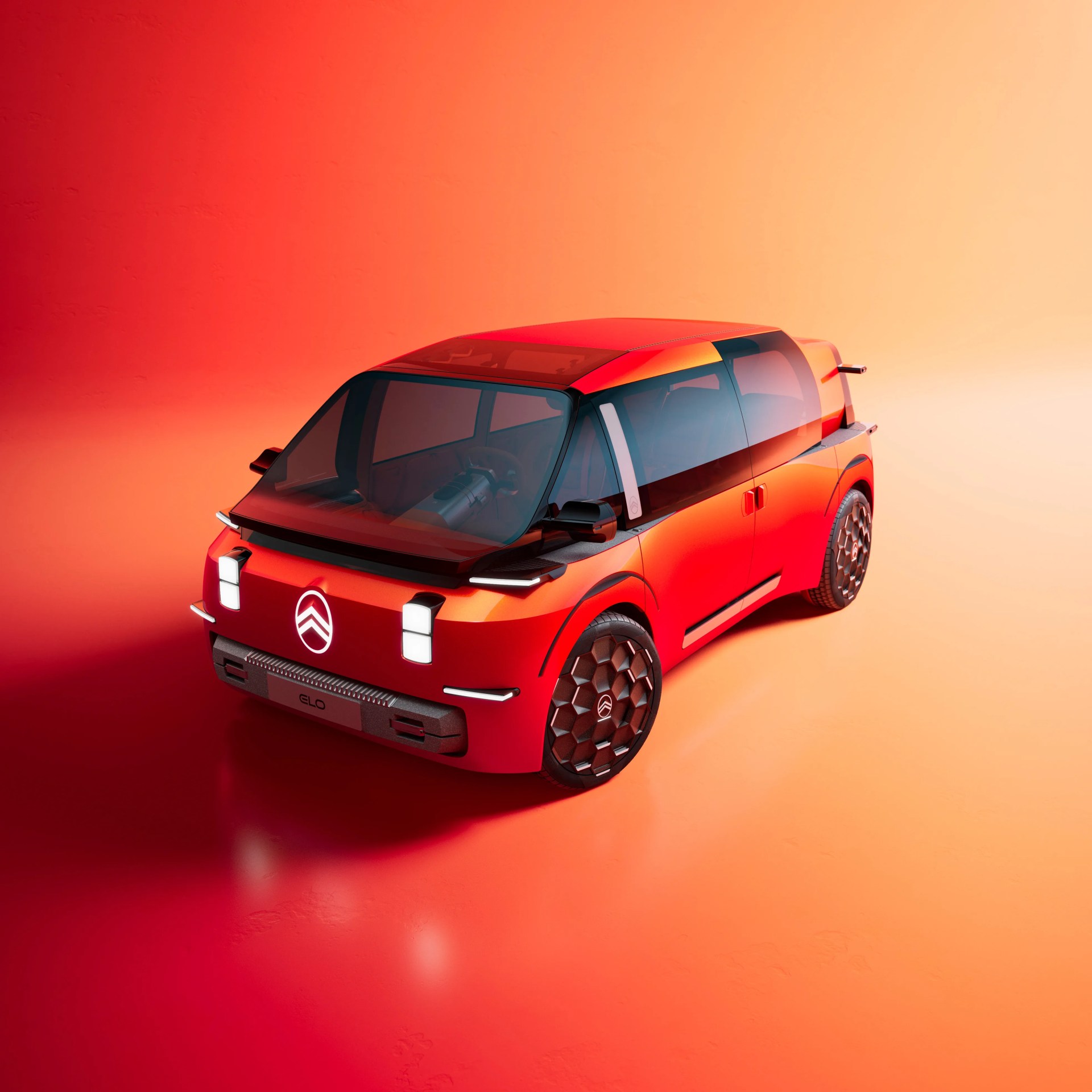 Compact red electric concept car with large tinted windows and hexagonal-patterned wheels on an orange gradient background.
