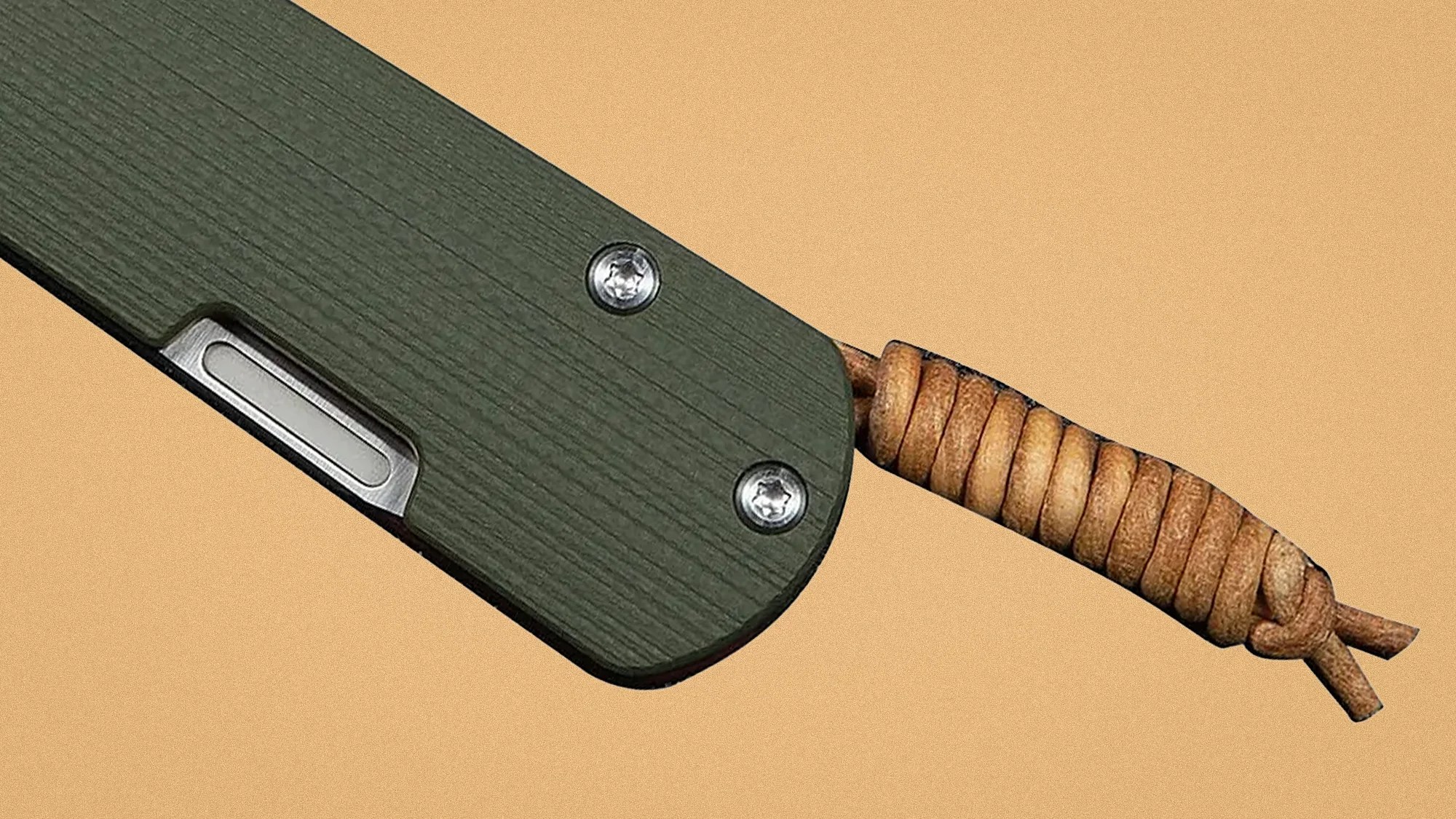 Close-up of a green textured knife handle with two screws and a brown leather lanyard looped through it.