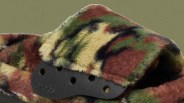 Close-up of a multicolored camouflage-patterned fuzzy Crocs strap with black plastic adjustment holes.