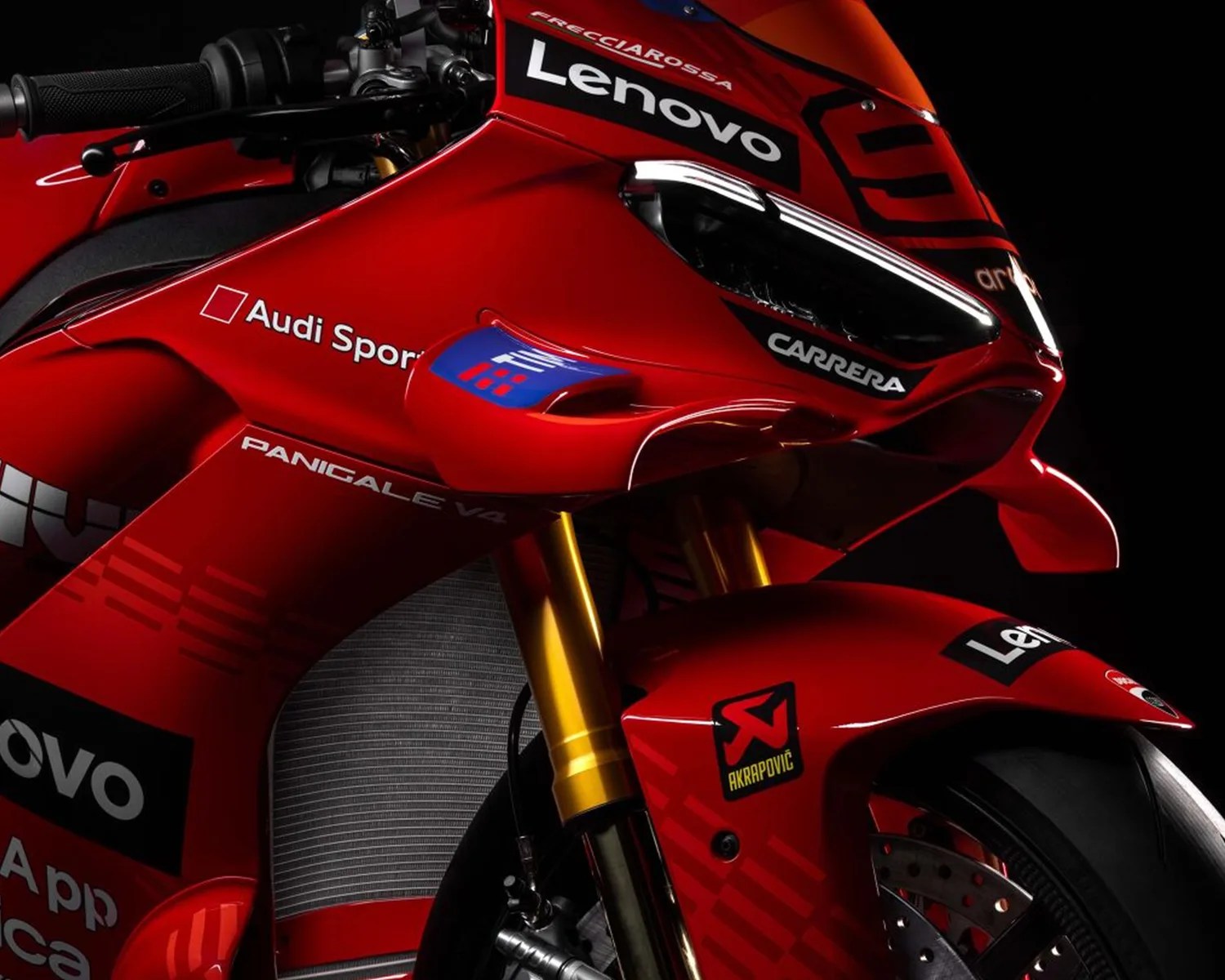 Close-up of a red Ducati Panigale V4 motorcycle front with Lenovo, Audi Sport, Carrera, and Akrapovič logos.