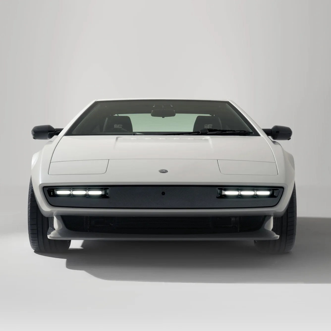 White sports car with pop-up headlights and LED daytime running lights, shown from the front on a plain background.
