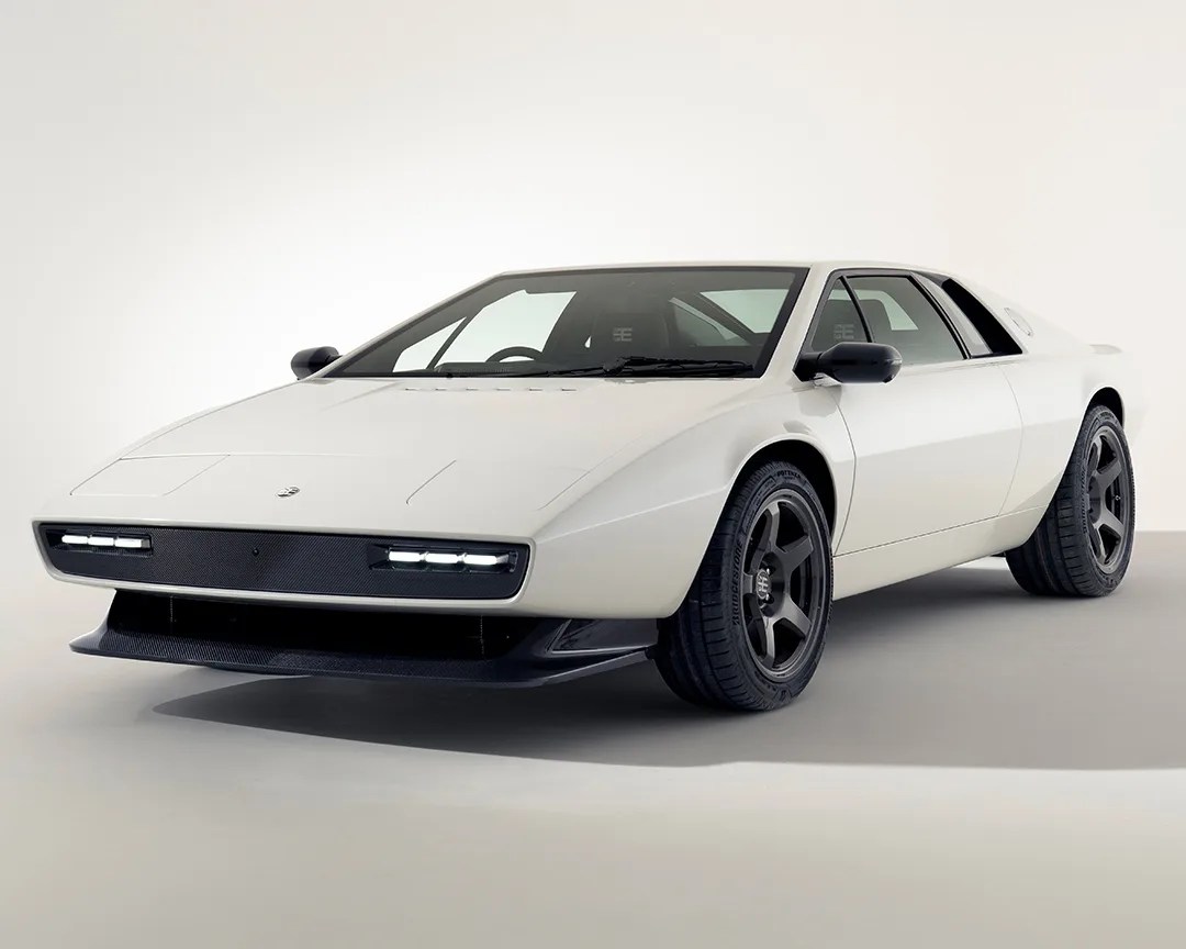 White vintage sports car with black wheels and LED headlights in a studio setting.