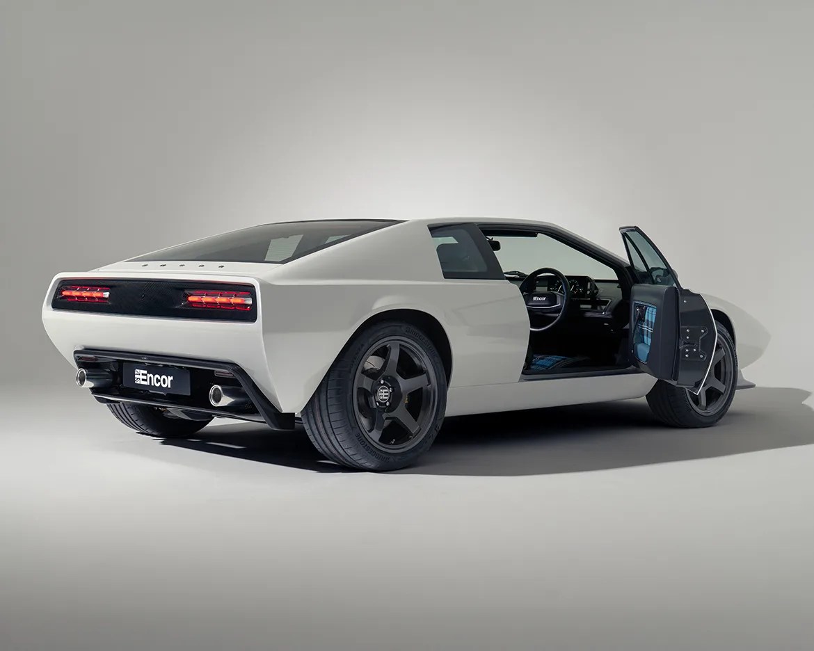 White Encor sports car with black wheels and open driver's side door in a studio setting.