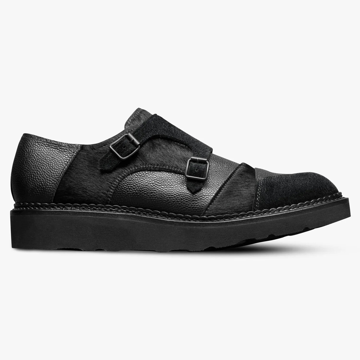 Black leather and suede double monk strap shoe with textured panels and thick sole.