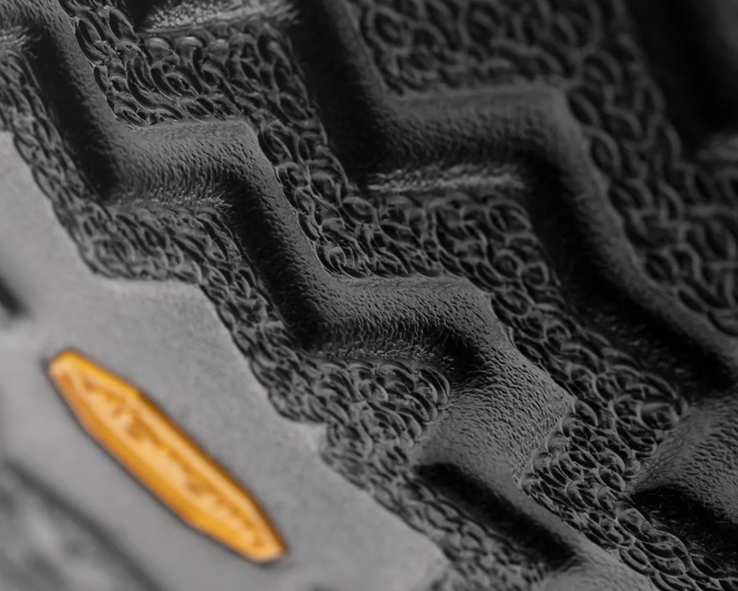 Close-up of a black textured rubber sole with a yellow Vibram logo.