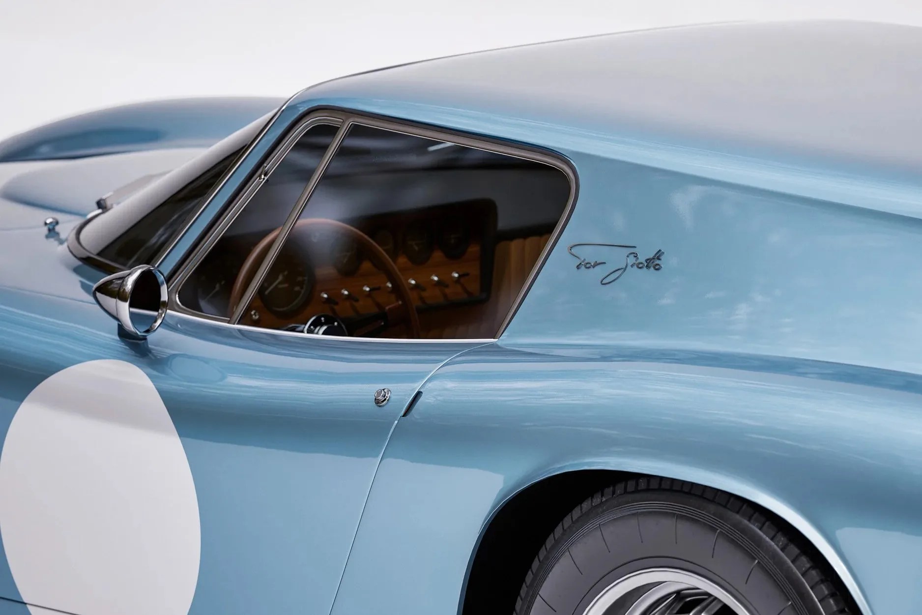 Close-up of a light blue vintage car door with a round white decal and "Tour Siotto" script near the window.