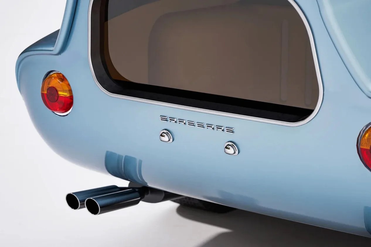 Rear view of a light blue car with dual exhaust pipes and round red and amber tail lights.