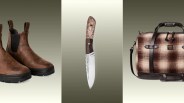 Pair of brown leather boots with black soles, a knife with a wooden handle and engraved blade, and a brown plaid duffel bag with leather straps.