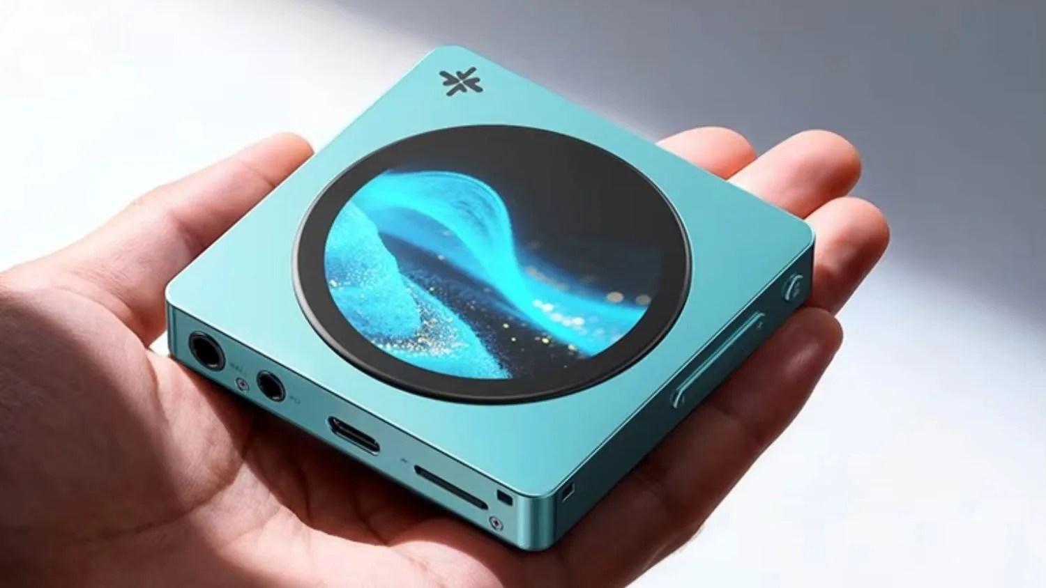Compact square turquoise digital device with circular screen displaying blue wave, held in a hand.