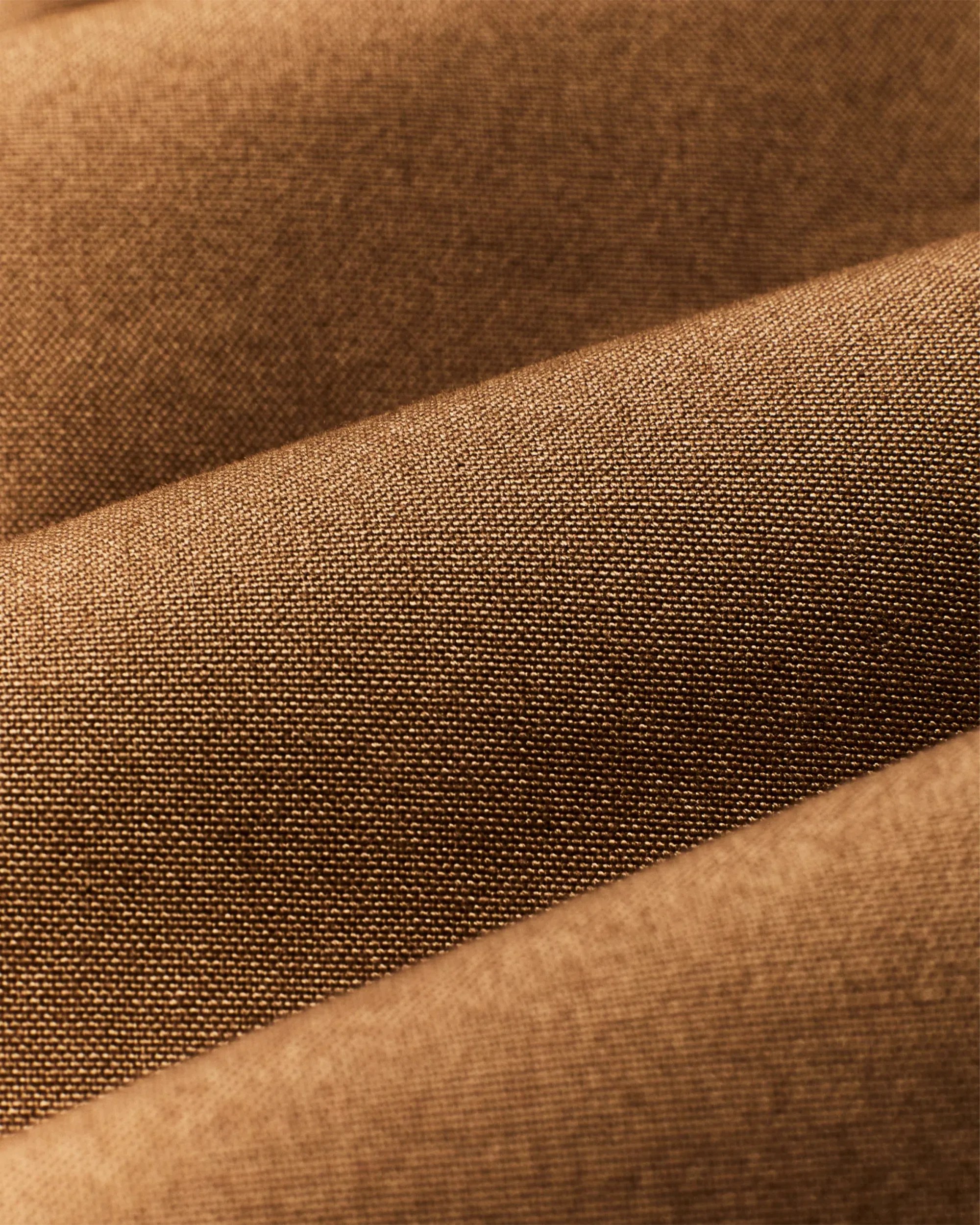 Close-up of tightly woven brown fabric with a smooth texture and slight folds.
