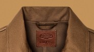 Brown canvas jacket collar with a stitched leather label reading "C.C. Filson Workshop Seattle Wash." and numbered 134/250.