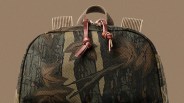 Backpack with camouflage fabric, leather zipper pulls, and ribbed fabric straps against a beige background.