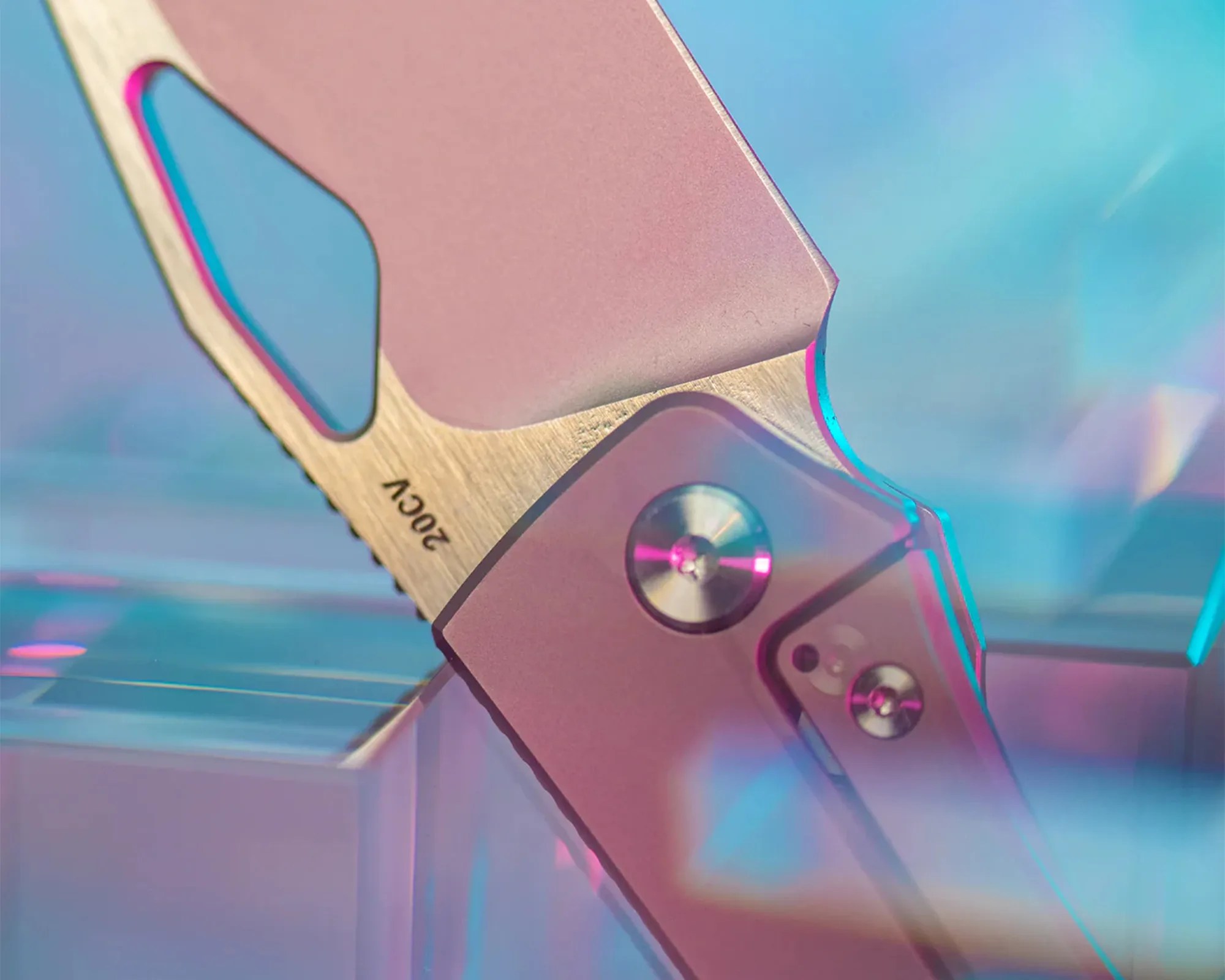 Close-up of a folding knife blade marked "20CV" with a metallic handle and screws, lit with pink and blue lighting.