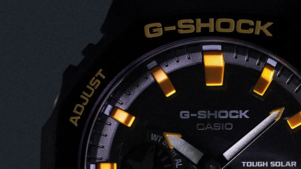 Close-up of a black Casio G-Shock watch face with yellow hour markers and silver hands.