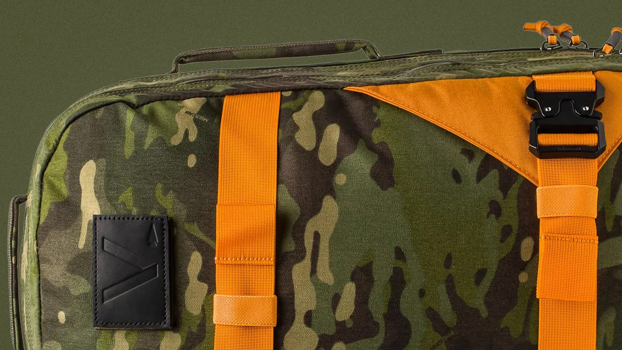 Close-up of a camouflage-patterned bag with bright orange straps and a black buckle.