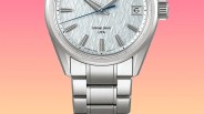 Silver metal wristwatch with textured white dial, blue second hand, date window, and linked bracelet band.
