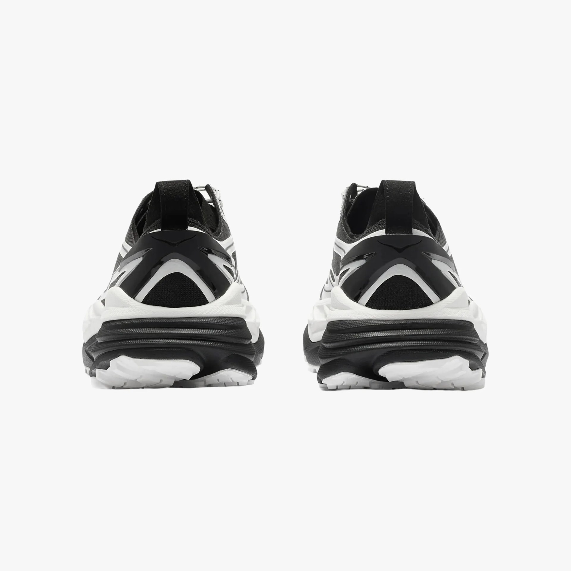 Pair of black and white athletic sneakers shown from the back with thick soles and pull tabs.