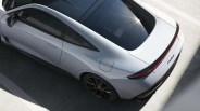 Silver sleek electric car with black roof and rear light bar parked on a concrete surface.