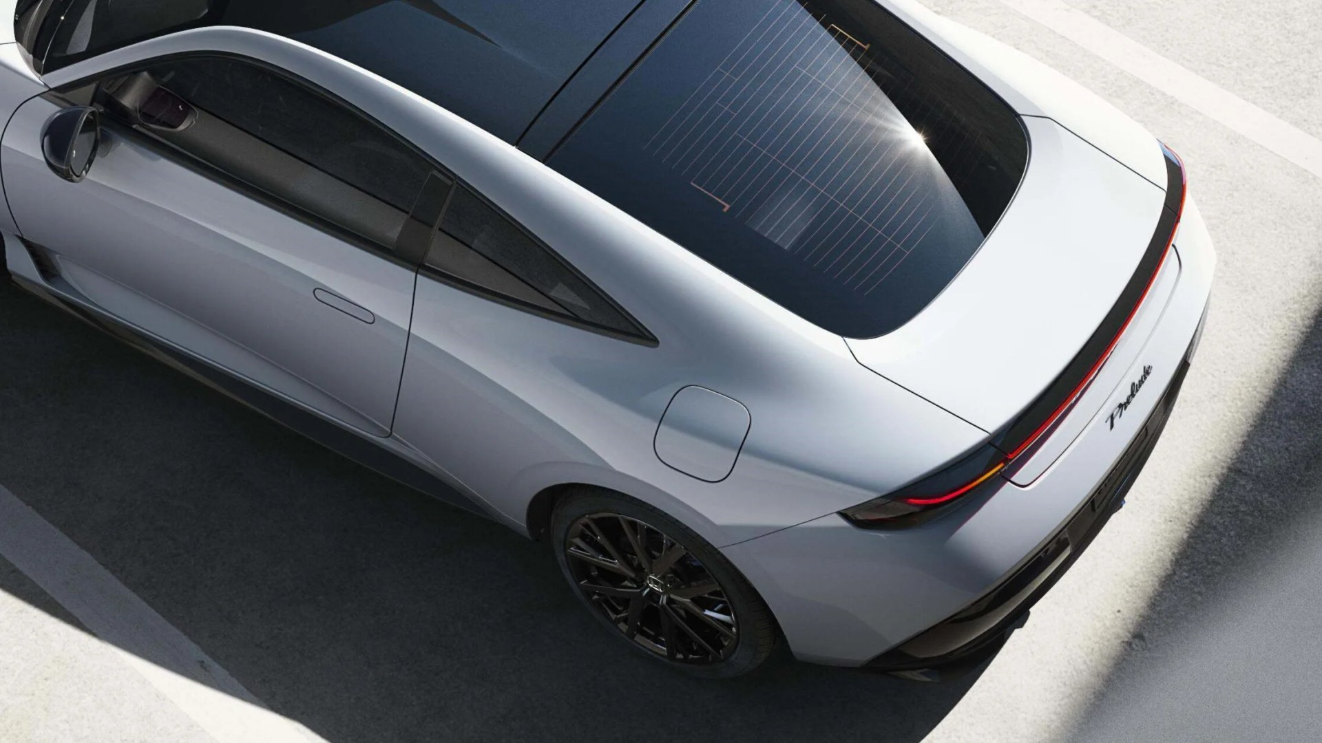 Silver sleek electric car with black roof and rear light bar parked on a concrete surface.