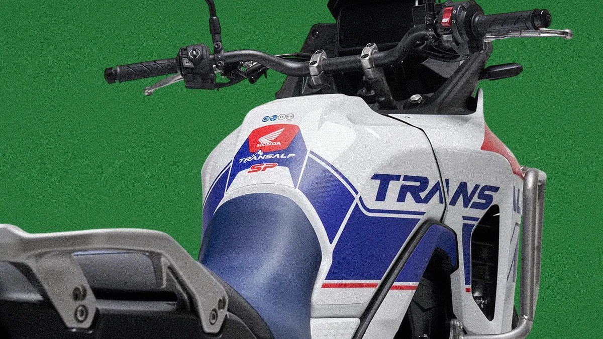 Close-up of a white Honda Transalp SP motorcycle fuel tank and handlebars with blue and red graphics.