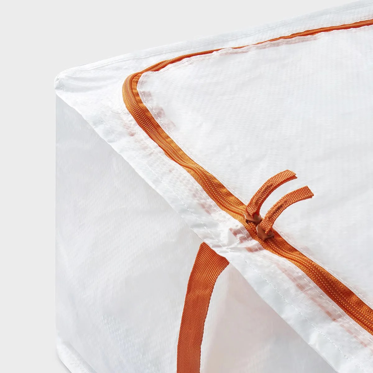 White fabric storage bag with orange zipper and handle on a light background.