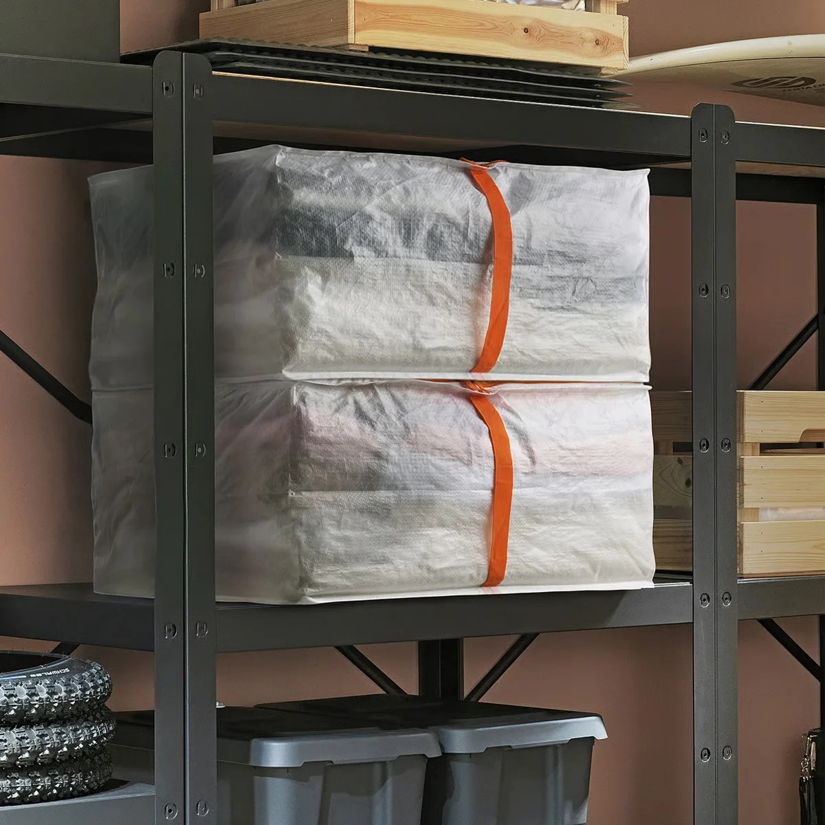 Two white fabric storage bags with orange straps stacked on a black metal shelf.