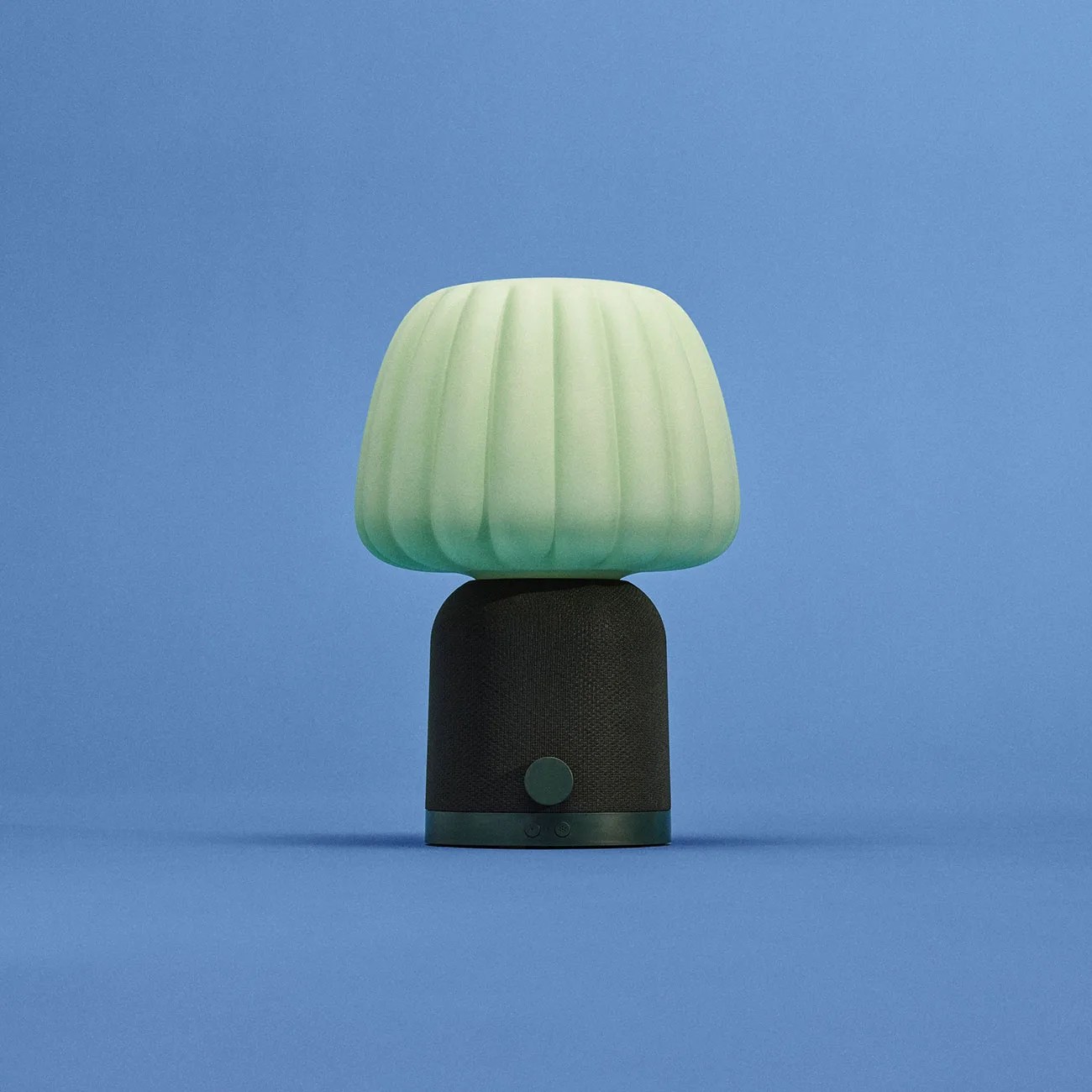 Small table lamp with a ribbed pale green shade and a black cylindrical base with control buttons.